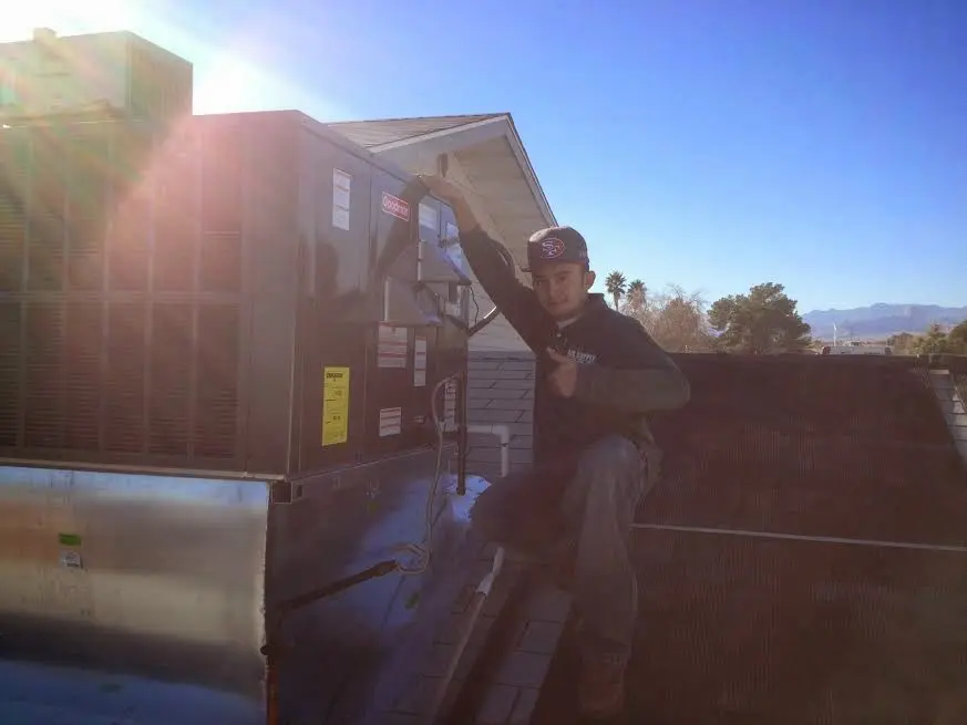 HVAC technician performing AC Tune-Up on a rooftop unit in Metairie