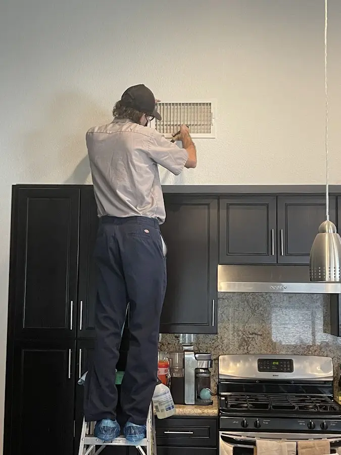 Technician inspecting an air vent during HVAC service in Metairie